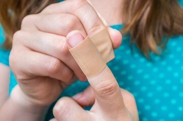 Woman puts a plaster on her injured finger