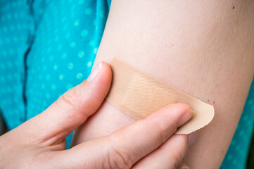 Woman puts a plaster on her injured arm