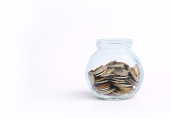 International coins in a glass jar on white background.