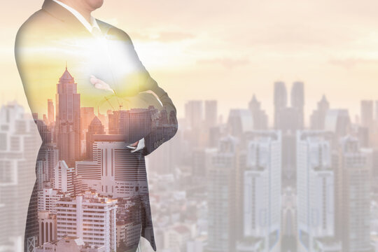 Double exposure of Businessman arms crossed and stand up, cityscape, urban and sunset in the evening as business and thinking vision of leader concept.