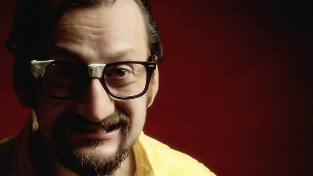 An angry ugly man wearing black broken eyeglasses (a stereotypical nerd), looking at the camera and sneering. Extreme close-up shot.

