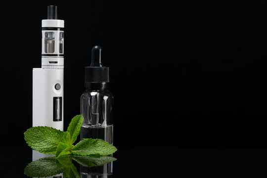 E-cigarette with reflection on a black background next to mint leaves