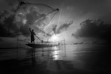 Fishermen on boat fishing with a large fishnet.Silhouette scene of the morning.