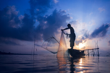 Fishermen on boat fishing with a large fishnet.Silhouette scene of the morning.