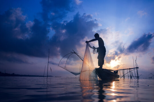 Fishermen on boat fishing with a large fishnet.Silhouette scene of the morning.