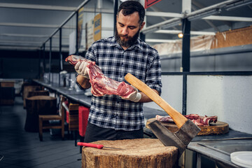 Bearded butcher holds fresh cut meat.