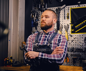 Biicycle mechanic with crossed arms holds cup key over.