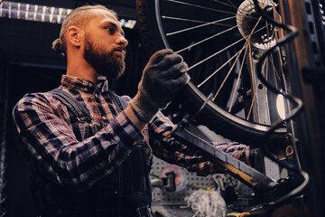 Obraz na płótnie Canvas Mechanic doing bicycle wheel service manual in a workshop.