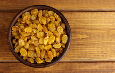 Raisins in bowl over wooden background