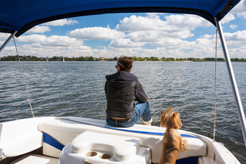 Man with his dog in motor boat on the river. Summer vacation yacht sailing, water sport. Yachtsman...
