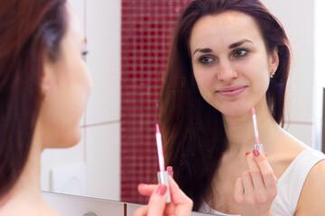 Young woman lip glossing in bathroom