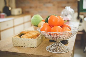 Bowl of healthy fresh fruit orange on table wooden and blurred of kitchen background