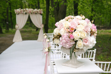 Beautiful bouquet in stone vase in front of wedding arch