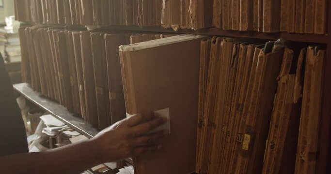 mans hand tooks a folder from the shelf