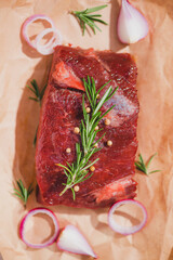 Raw beef on a cutting board  with spices and ingredients for cooking.
