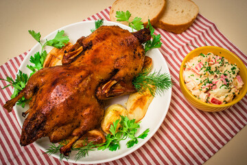 Festive baked duck with apples close-up on a plate on a table.