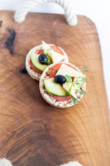Wholemeal bread snack with cheese, avocado, olive, tomato and greens