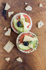 Wholemeal bread snack with cheese, avocado, olive, tomato and greens