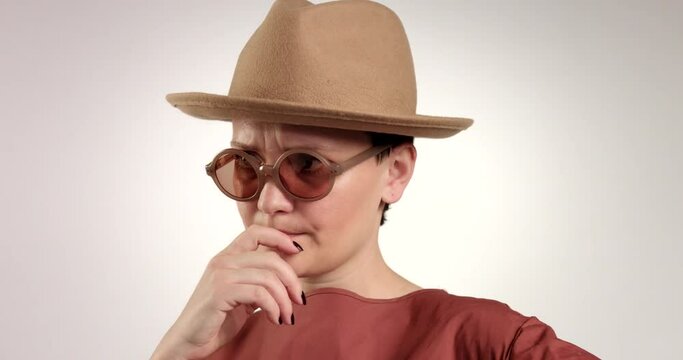 serious woman in hat and sunglasses in doubt then