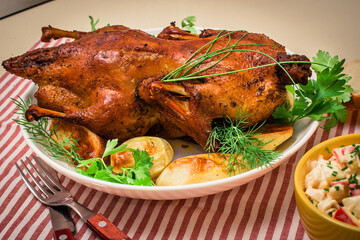 Festive baked duck with apples close-up on a plate on a table.