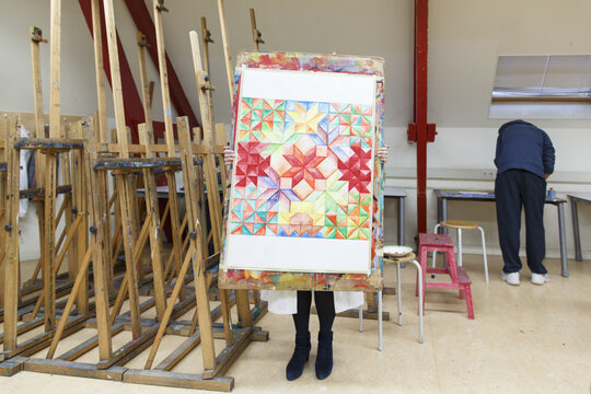 a high school student holding up a painting made at creative lessons