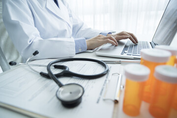 Female doctor is typing in laptop computer