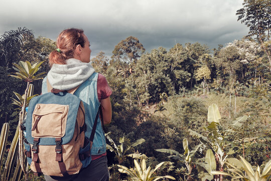 Hiker woman traveler with backpack looking at wild jungle.