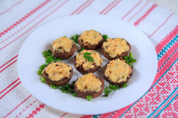 The champignons stuffed with chicken and greens under cheese on a white plate