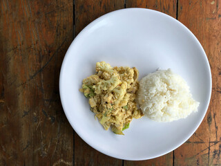 Fried cauliflower with tofu and egg in white pate on wooden table.