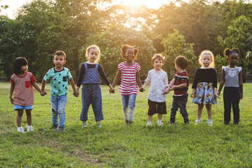 Group of kindergarten kids friends holding hands playing at park - obrazy, fototapety, plakaty