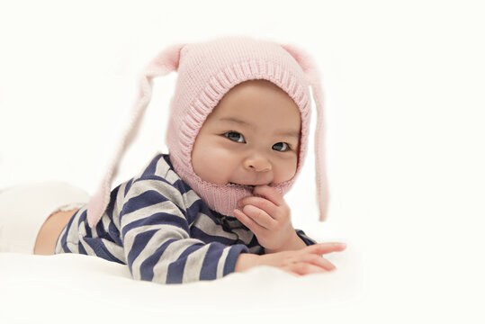 Asian cute baby girl wearing pink rabbit hat on her head on white background