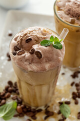 Tasty cold refreshing drink with coffee, milk, chocolate ice cream and ice in glass on ice background. Closeup.