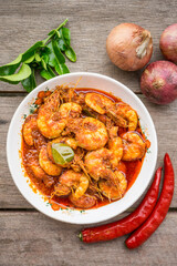 Chili prawns or know as "Sambal Udang" in a white plate over wooden background. Asian cuisine food.