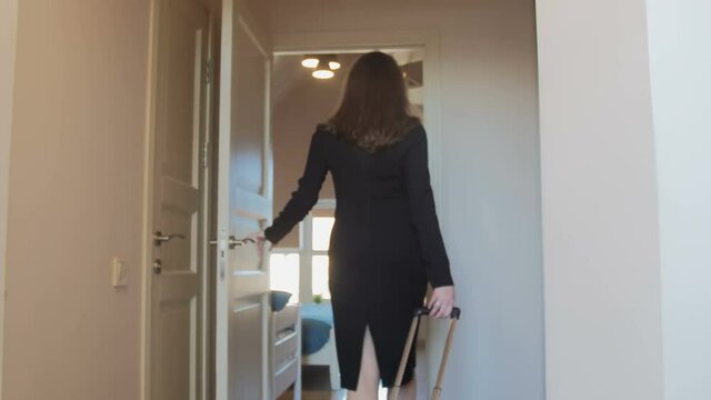4K video of elegant businesswoman opens door and enters hotel room