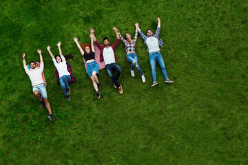 Group of young people laying on the grass, happy, smiling