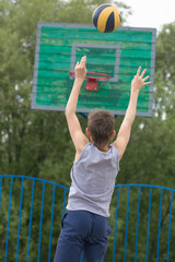 Obraz premium Teen in a T-shirt and shorts throws the ball into the ring