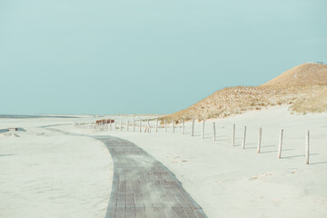 Boardwalk on a empty beach with dunes and grass in notrh Nethelands at windy day