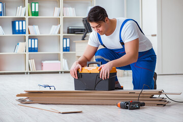 Young worker working on floor laminate tiles