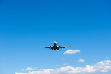 Fototapeta na wymiar Airplane in blue sky front view from ground