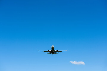 Airplane in the clear blue sky, preparing to landing, front view from the ground