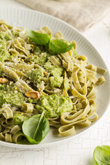 Tasty appetizing italian pasta with sauce pesto and pistachios on white plate. Closeup.