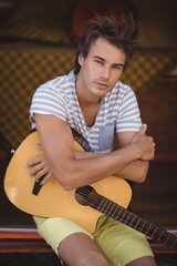 Obraz premium Portrait of handsome man with guitar sitting in van