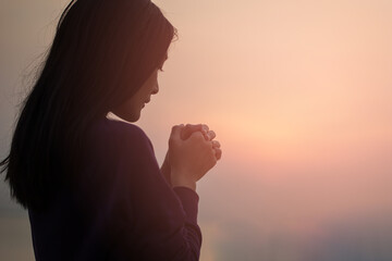 Christian woman praying worship at sunset. Hands folded in prayer. worship god with christian...