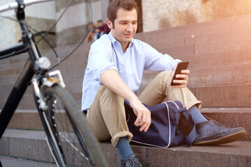 Fototapeta na wymiar Man is resting next to his bike and using mobile phone