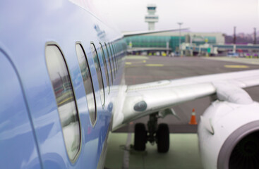 Travel Internationally in Luxury Private Jet for the Wealthy and Rich Leisure Life. Side of Jet Airplane Close-Up. Left Side. Airport Terminal and Landing Take Off Watch Tower.