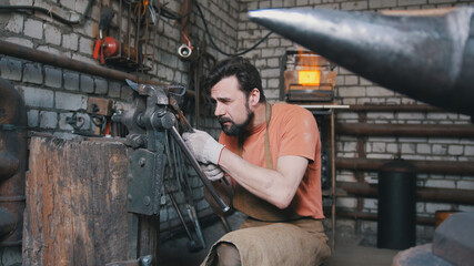 Fototapeta na wymiar Blacksmith working with hot metal at the forge