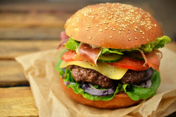 Burger with bacon on wooden table.