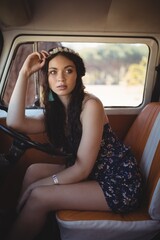 Fototapeta na wymiar Young woman looking away while sitting in motor home