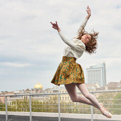 Young caucasian fashion ballerina leaping on the roof