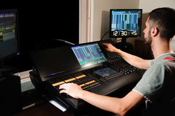A lighting engineer works with lights technicians control on the concert show. Professional light...